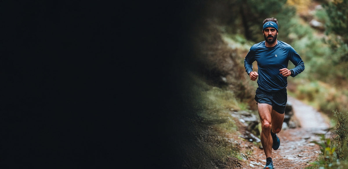 Man running on a forest trail wearing athletic gear.