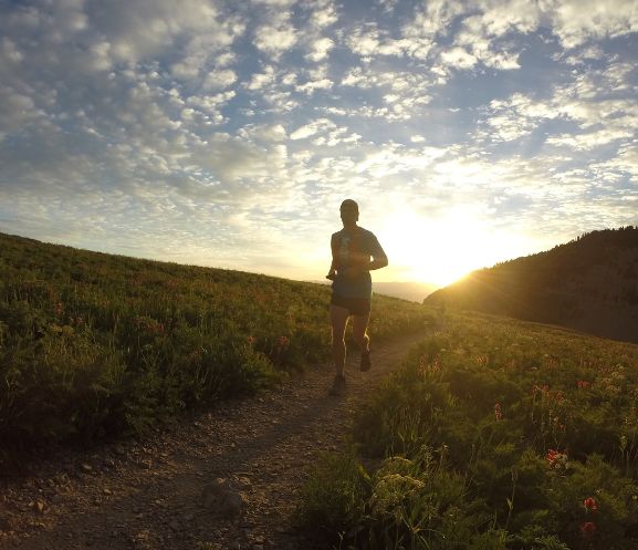 Silhouette of person running on a trail at sunrise.